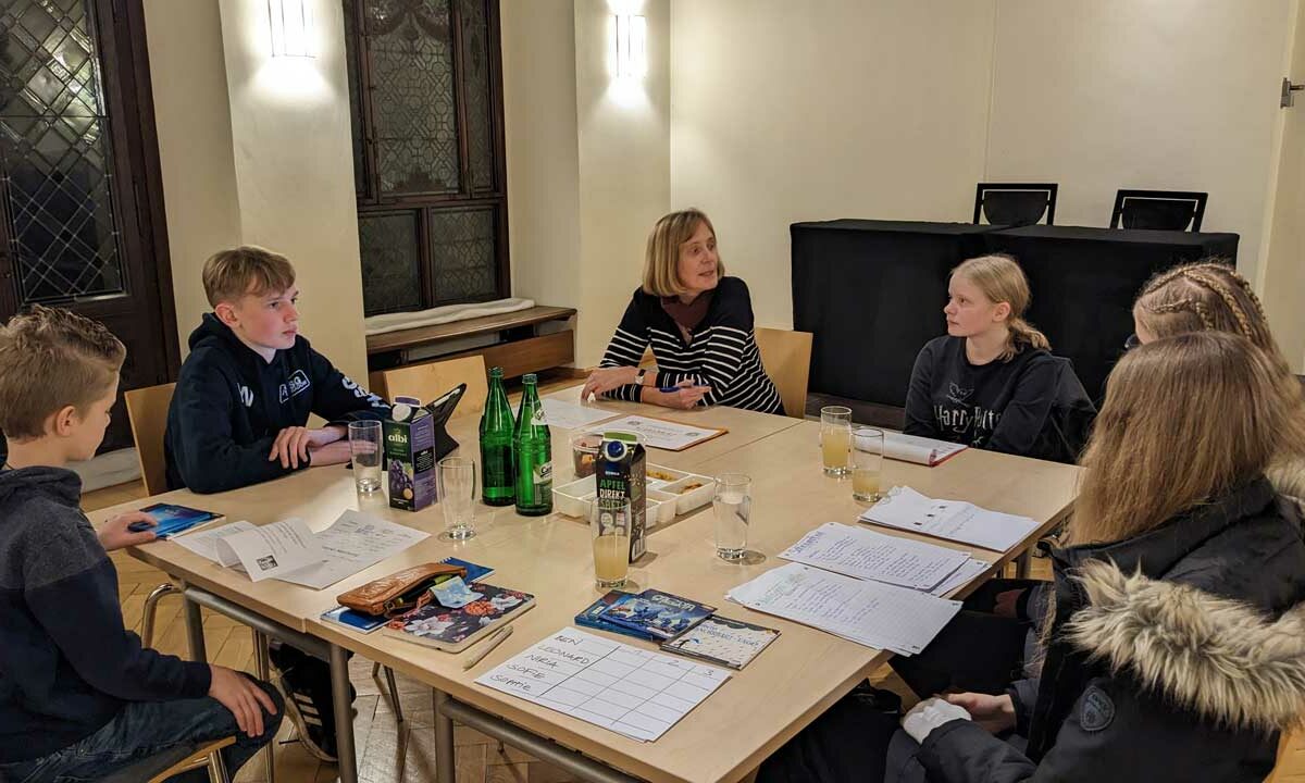 Kinderjury sitzt zusamen am Tisch um über den Hörbuchpreis zu beraten.